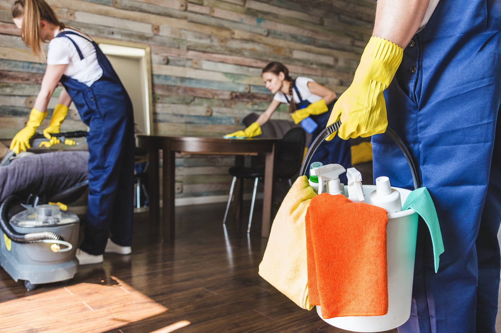 Cleaning crew cleaning a luxurious living room, using cleaning supplies and wearing gloves