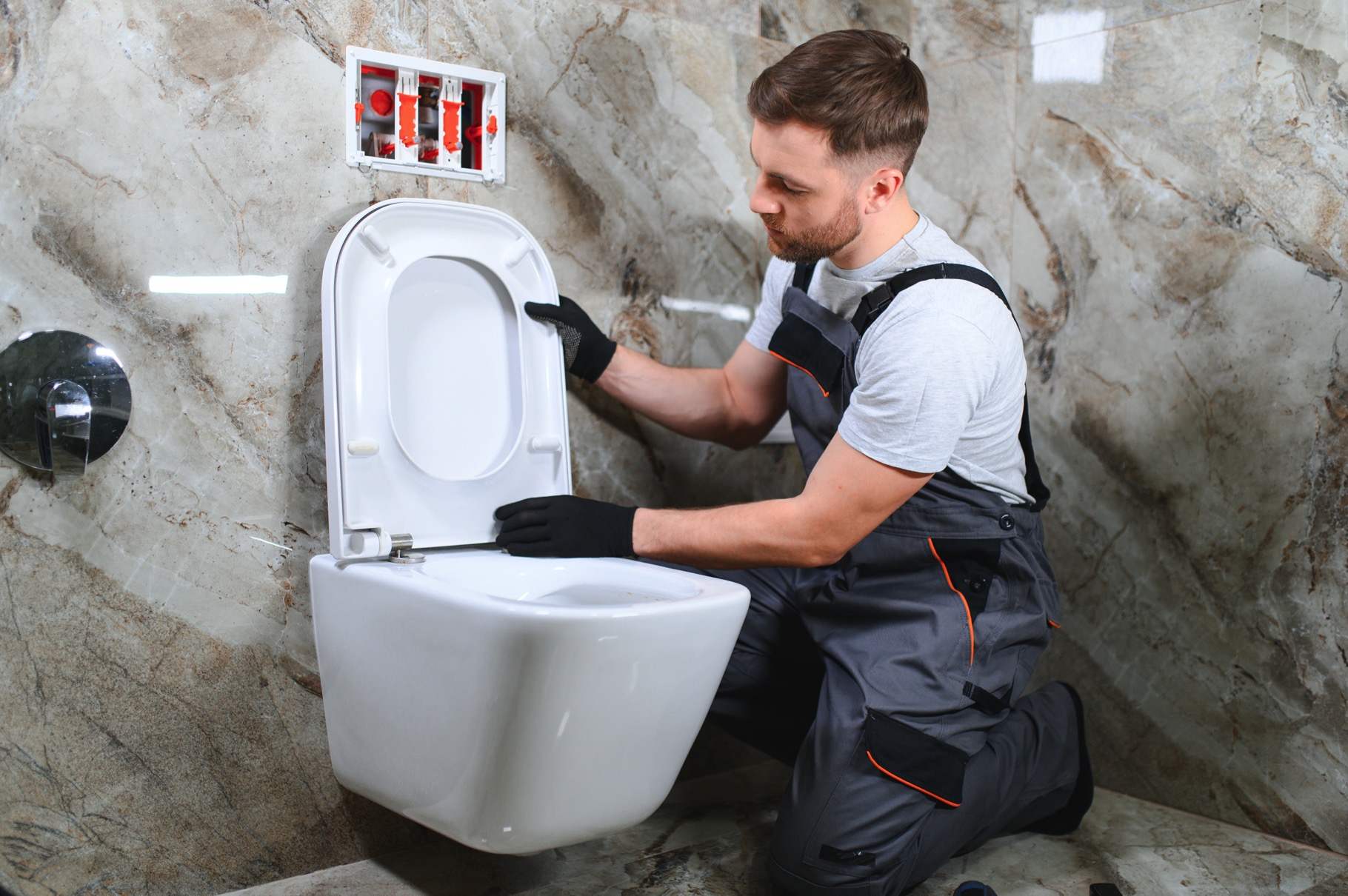 Plumber installing recessed toilet in modern bathroom